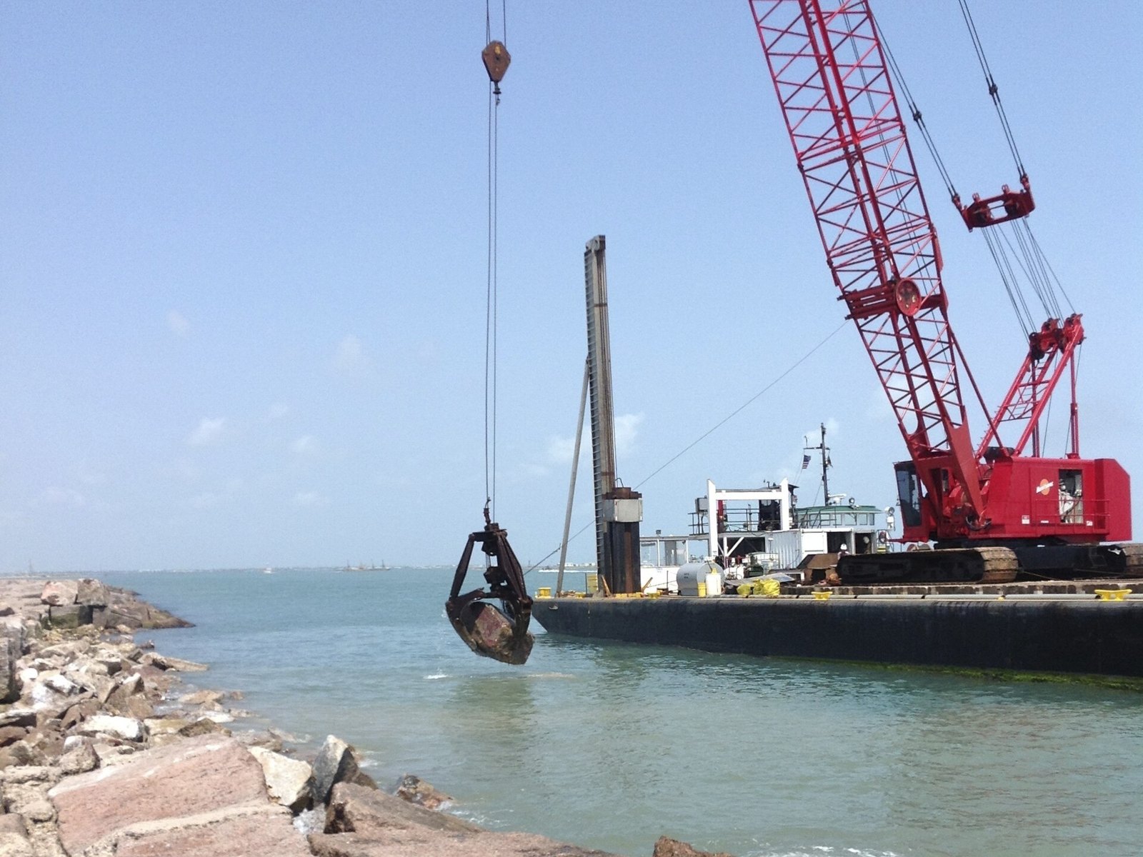 A crane barge repairing the rock jetty at the entrance to the Brownsville Ship Channel