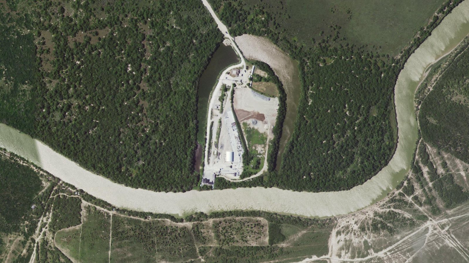 Aerial view of SpaceX's Massey's test site, a strip of pavement and buildings inside a bend of the Rio Grande, surrounded by brush